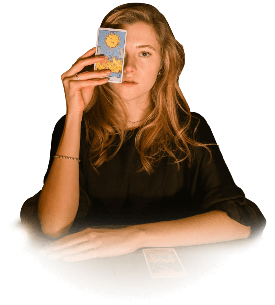 A woman holding a tarot card in front of her face.